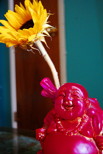 Small Laughing Buddha with flower (image via Buddha Collective)